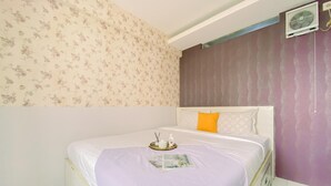 Un dormitorio con una cama, una mesita de noche, aire acondicionado de pared y papel tapiz floral.