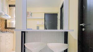 Un baño con dos lavamanos blancos, un espejo encima y una puerta a la derecha.