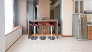 Une cuisine moderne dotée d’un réfrigérateur encastré, d’un plan de travail en bois et de trois tabourets de bar.