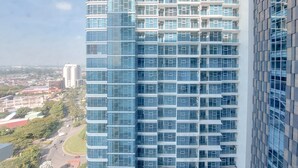 Un edificio de gran altura con fachada de vidrio moderna, varios balcones y vistas de la ciudad circundante.