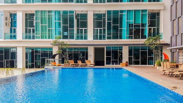 Un hotel moderno con una amplia piscina cubierta, tumbonas y vistas del exterior del edificio.