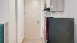 A narrow hallway with a closed door, a refrigerator, and a built-in microwave shelf. - Serene Living Studio Tokyo Riverside Pik 2 Apartment (Teluknaga)