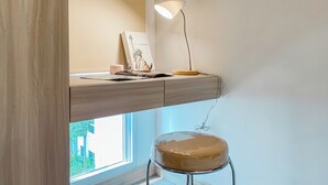 A desk with a lamp, a framed picture, and a cake on a stand. - Serene Living Studio Tokyo Riverside Pik 2 Apartment (Teluknaga)