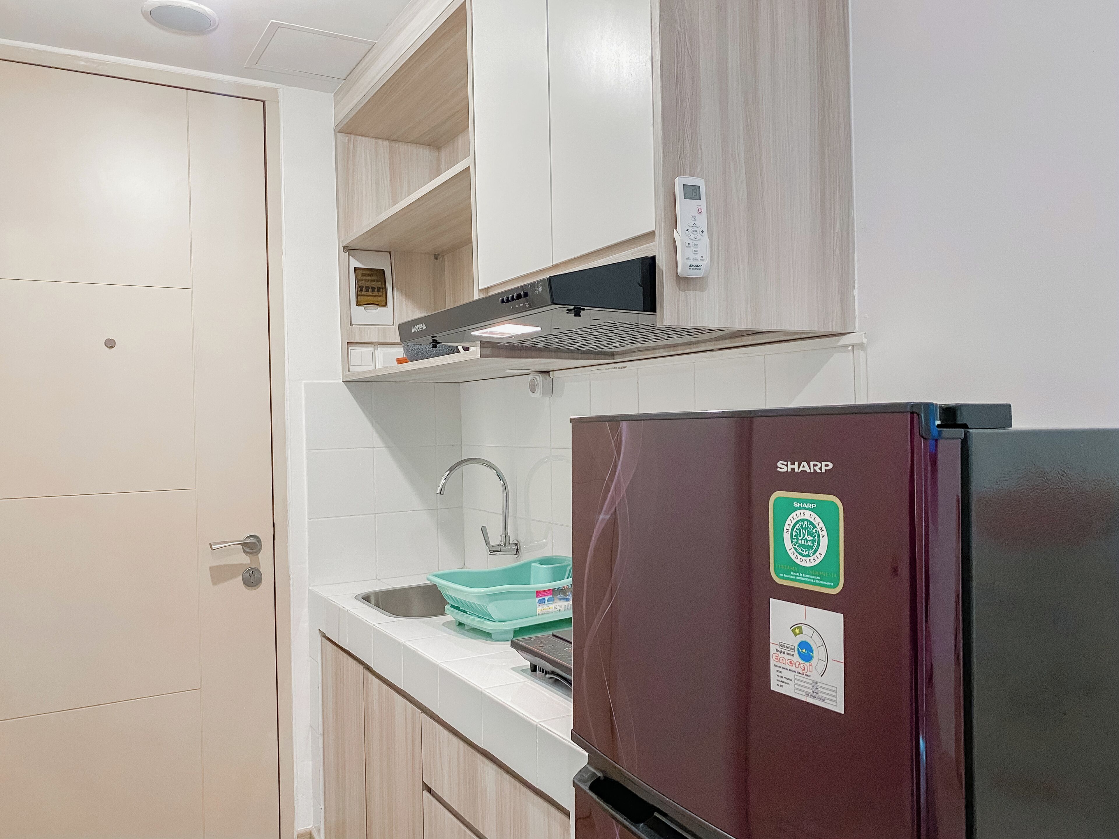 Una cocina con microondas integrado, un fregadero y un refrigerador Sharp.