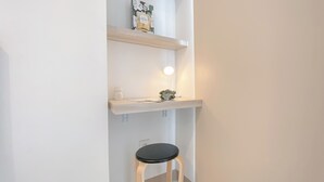 Un petit couloir étroit, avec un tabouret en bois et une étagère où sont disposés des objets décoratifs.