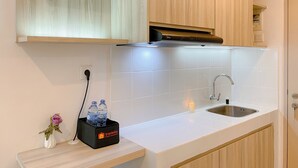 Une cuisine moderne avec des carreaux blancs, un évier en acier inoxydable, des armoires en bois et un sac de voyage noir posé sur le comptoir.