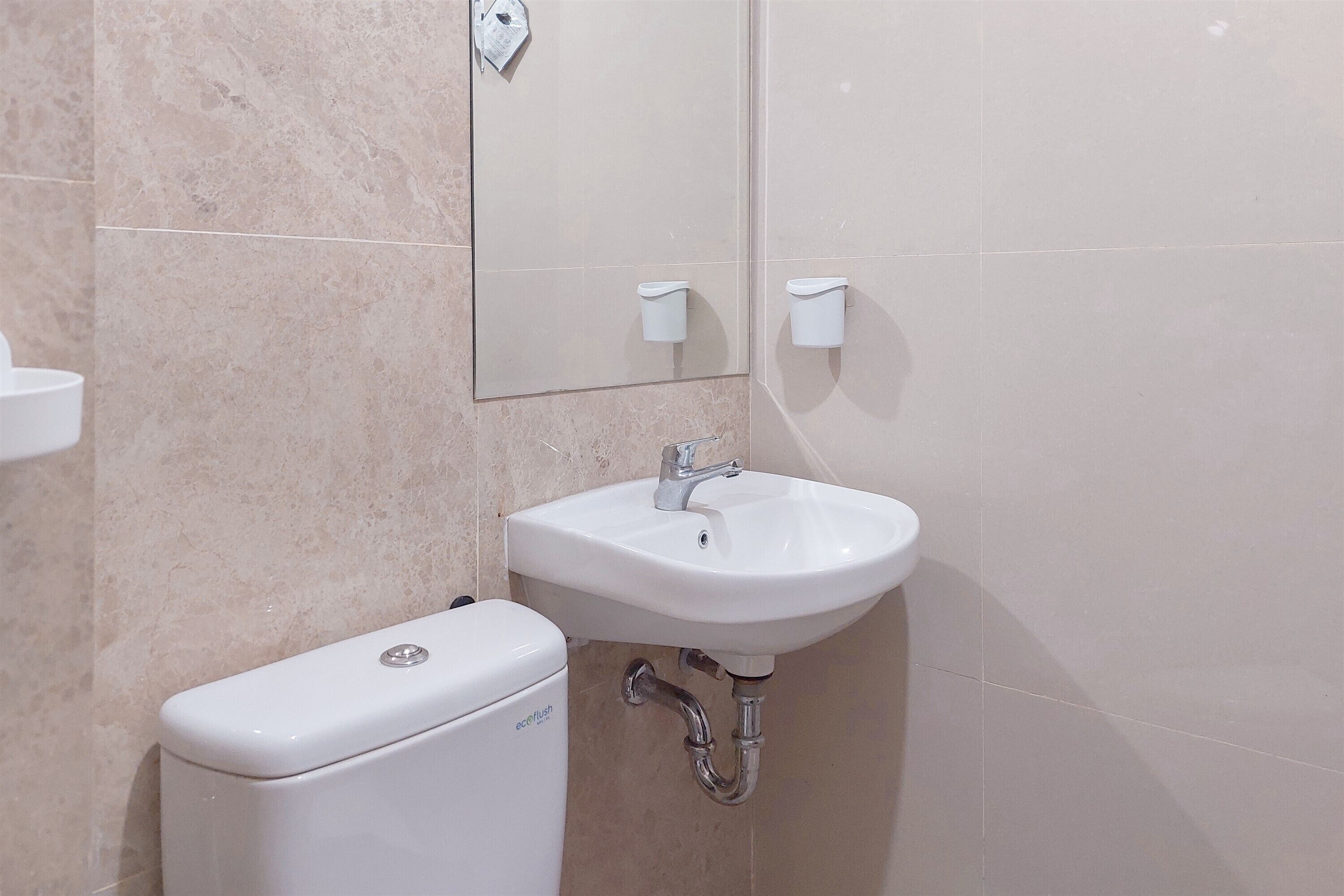 A bathroom with a white toilet, a sink, and a mirror.