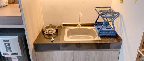 A compact kitchen with a sink, a coffee machine, and a dish rack.