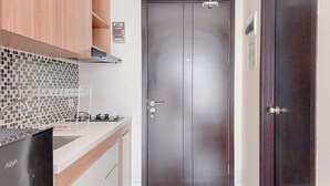 Eine moderne Küche mit einem Edelstahl-Kühlschrank, einer Doppeltür mit Griff sowie einer gefliesten Spritzschutzwand.