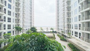 A modern apartment building with multiple balconies, a central courtyard with greenery, and a view of the distant landscape. - Warm And Simply Look Studio Apartment Tokyo Riverside Pik 2 (Teluknaga)
