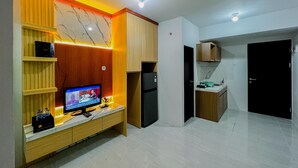 Una cocina moderna con electrodomésticos integrados, un armario de madera y un televisor sobre una encimera de mármol.