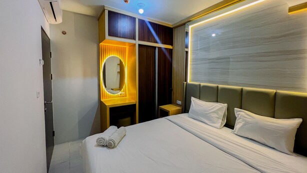 Una habitación de hotel con una cama, un tocador con espejo y un ventilador de techo.