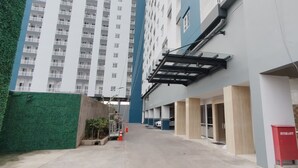 Un edificio moderno con fachada plana, ventanas amplias y una pared verde en un lateral.