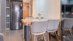 Et moderne køkken med et rustfrit stål køleskab, et spisebord med fire stole og en vase med blomster på bordet.