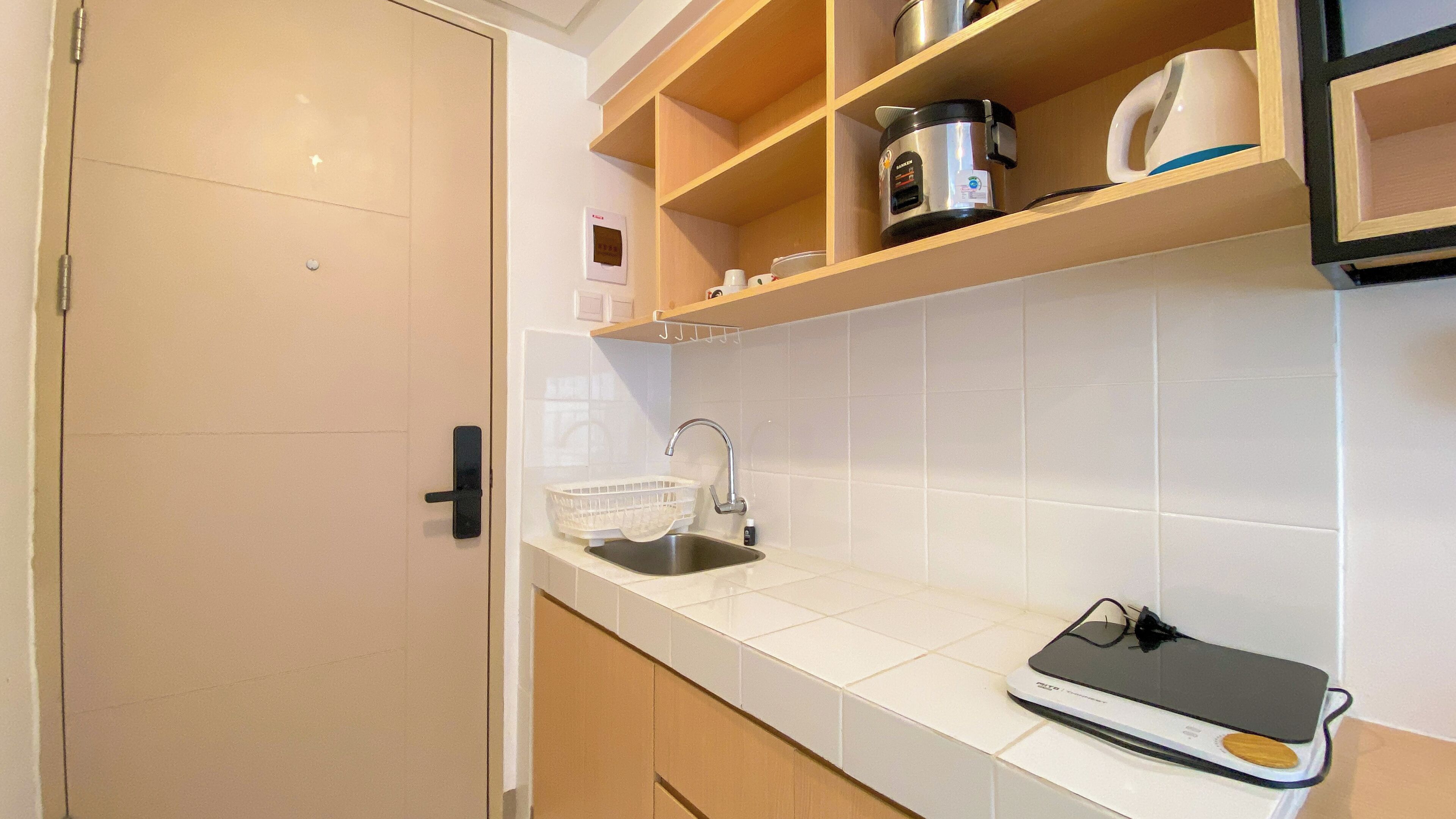 A kitchen with a white tiled backsplash, a stainless steel sink, a coffee maker, and a rice cooker on wooden shelves.