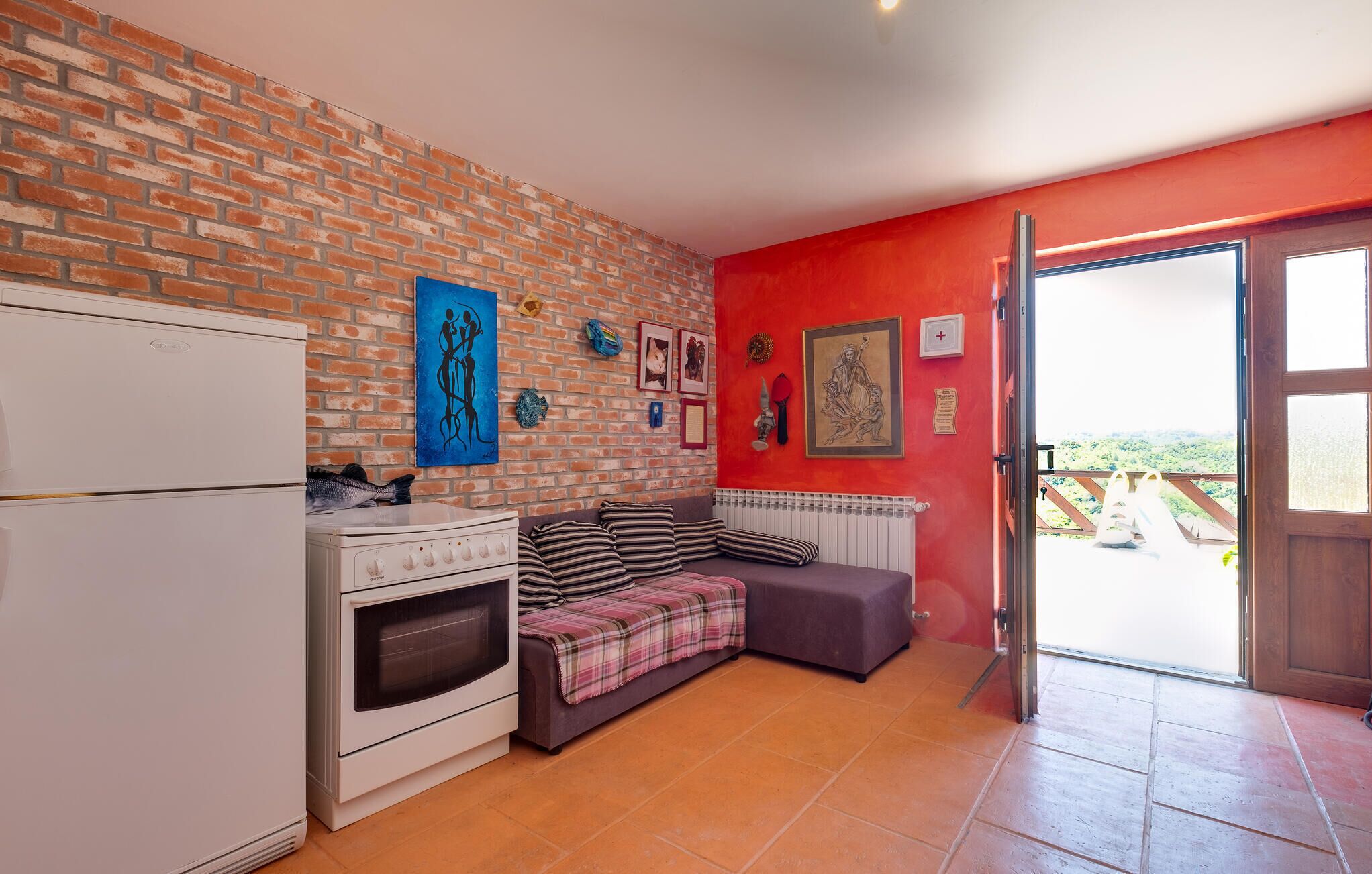 A compact kitchen with a brick wall, a white refrigerator, a stove, and a dining area with a bench.
