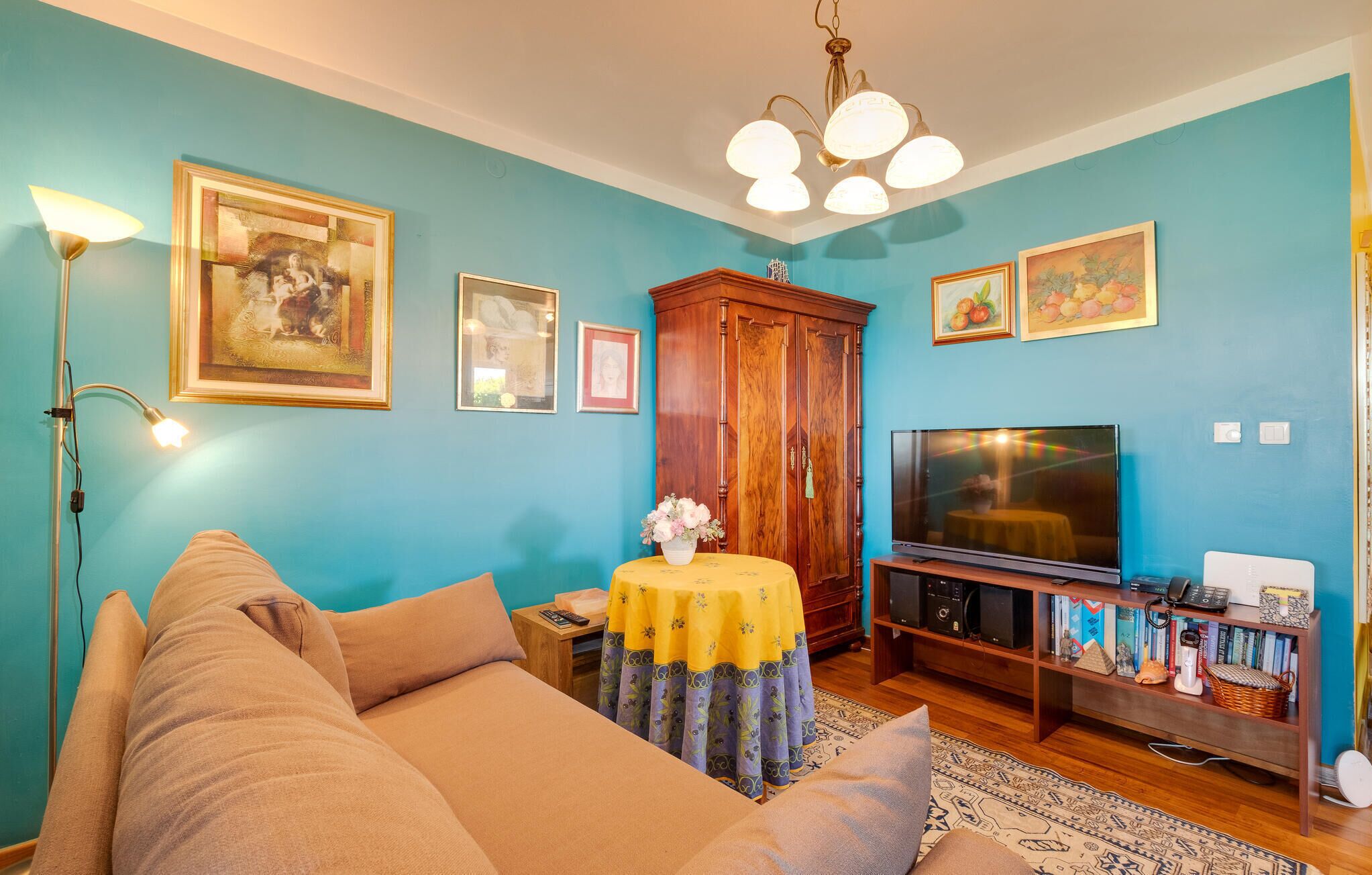 A living room with a sofa, a TV, a cabinet, and a table with a vase.