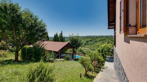 A house with a stone staircase leading to a wooden deck overlooking a lush green landscape.
