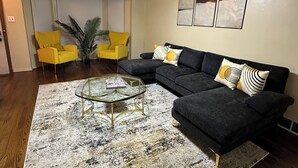 A living room with a sectional sofa, a glass coffee table, and a yellow armchair.