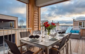 A dining area with a table set for four, a wooden deck, and a view of the sky and buildings. - Stunning apartment in Olpenitz (Olpenitz)