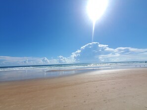 Une plage avec un ciel dégagé et un soleil éclatant.