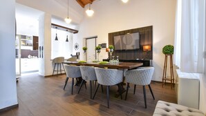 A modern dining area with a wooden table, four upholstered chairs, and a television mounted on the wall. - Cozy home in Trecastagni (Trecastagni)
