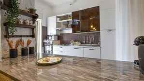 A modern kitchen with white cabinets, a marble countertop, and a built-in oven. - Cozy home in Trecastagni (Trecastagni)