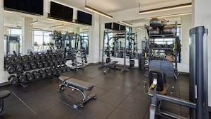 Une salle de sport moderne équipée de divers appareils d’exercice, notamment des haltères, des appareils de musculation et des appareils de cardio.