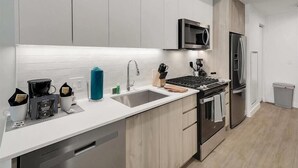 A modern kitchen with white cabinets, a stainless steel refrigerator, a microwave, and a dishwasher. - Central Studio | Pool/Spa/Hottub | Close to Shops & Parks (Phoenix)