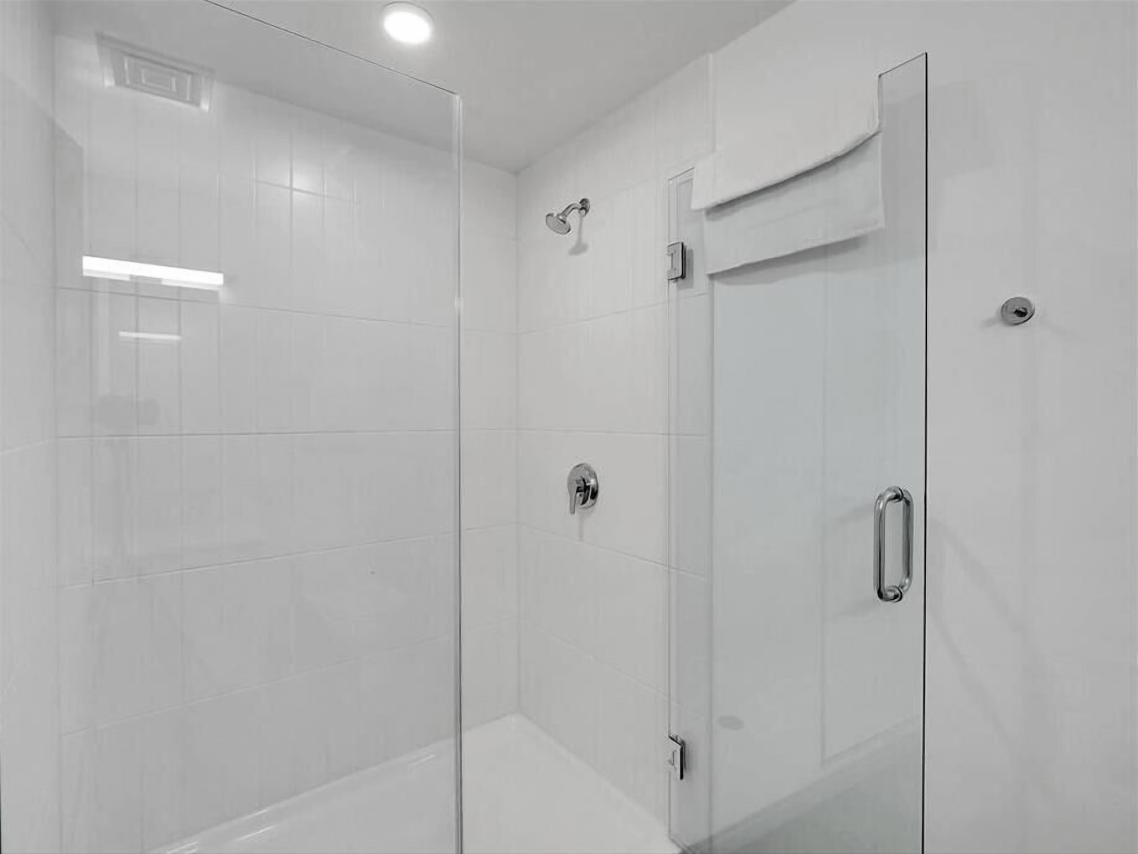 A modern shower enclosure with a glass door, a towel rack, and a showerhead.