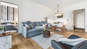 Una sala de estar moderna con un sofá gris, una mesita de centro y un comedor con una mesa y sillas blancas.