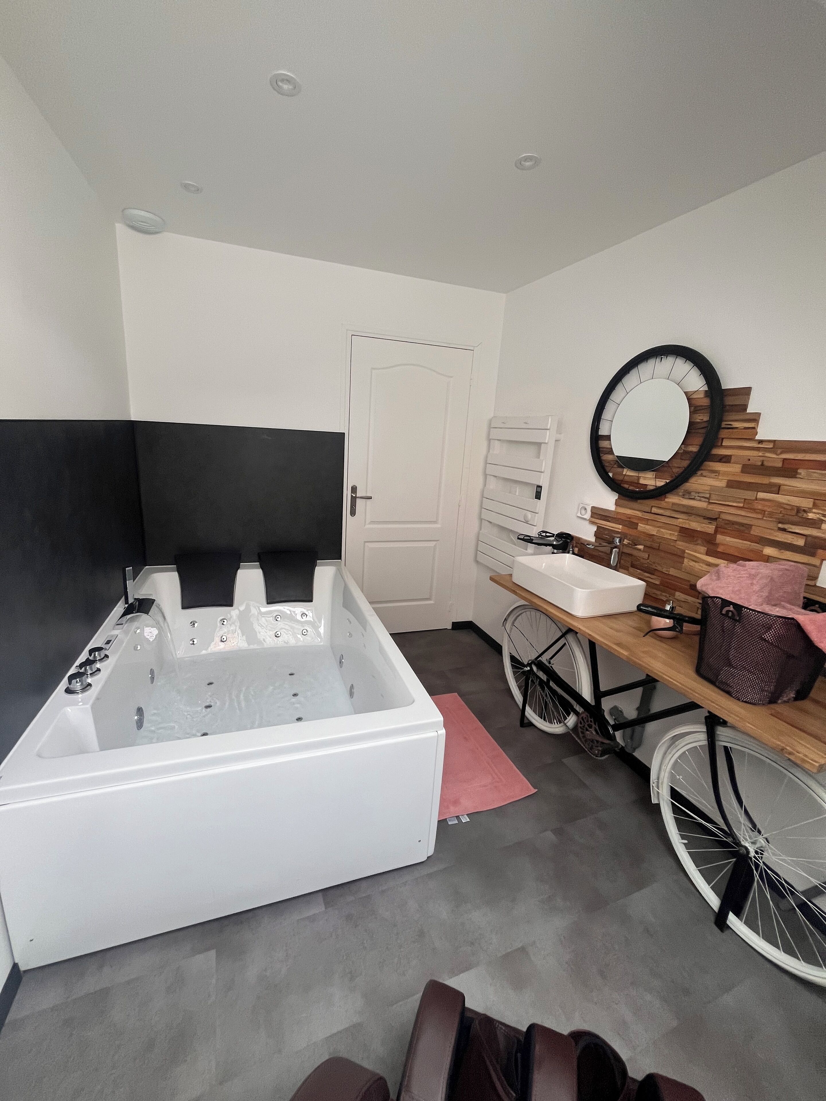 A bathroom with a bathtub, a sink, a mirror, and a bicycle.