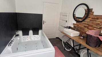 A bathroom with a bathtub, a sink, a mirror, and a bicycle.