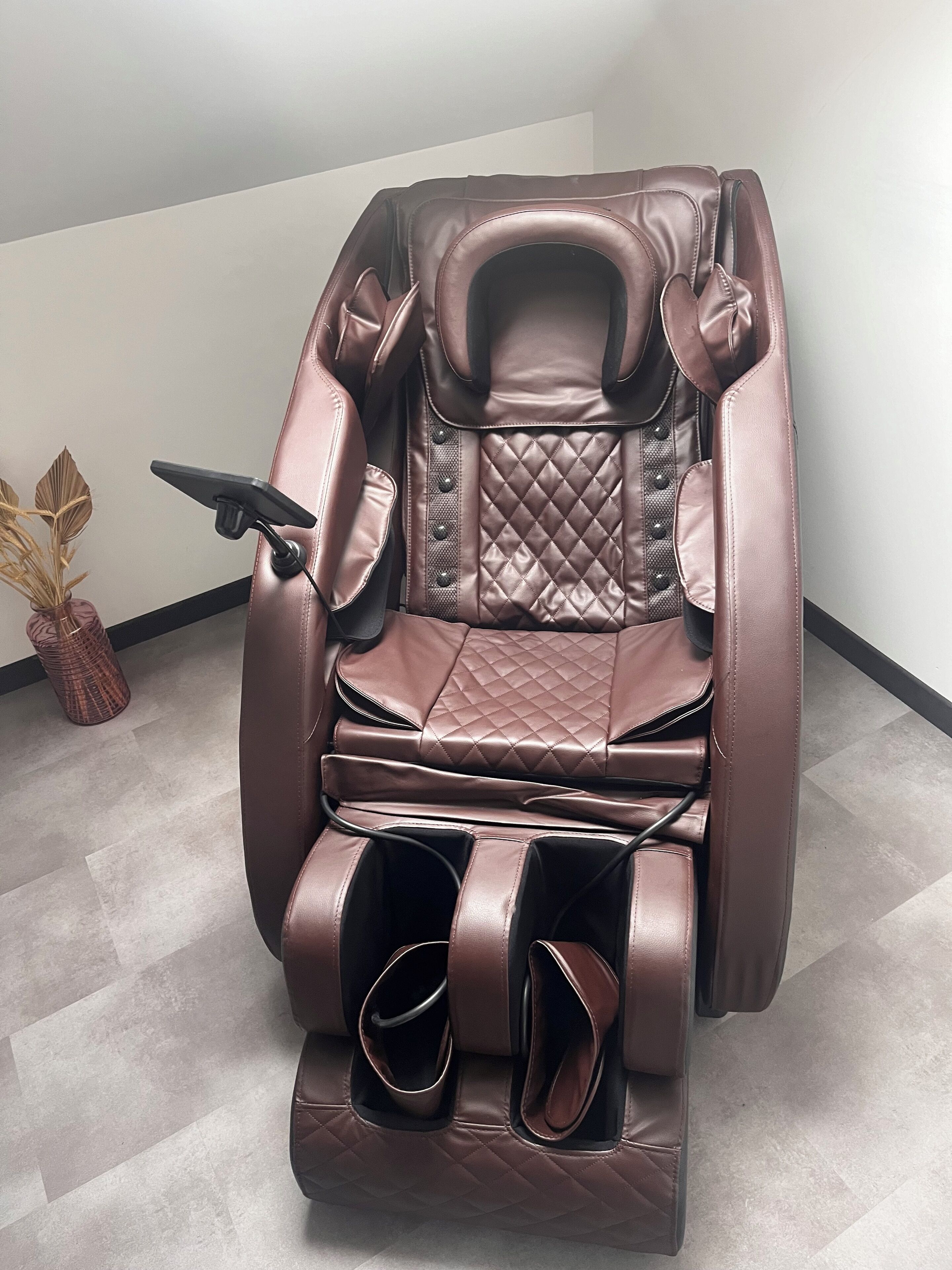 A massage chair with a cushioned seat and backrest, adjustable footrest, and a control panel.
