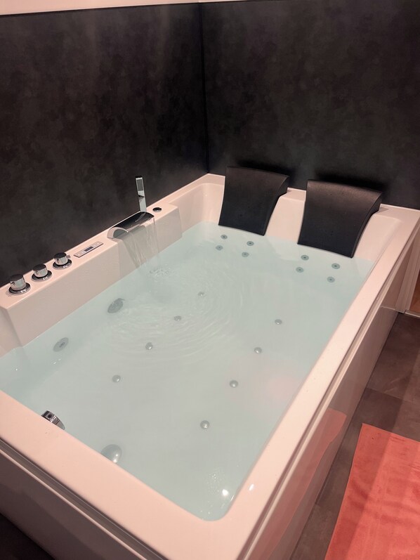 A modern bathtub with a control panel and jets, set against a dark wall. - A Getaway to the Heart of Avranches, Near Mont Saint-Michel (Avranches)