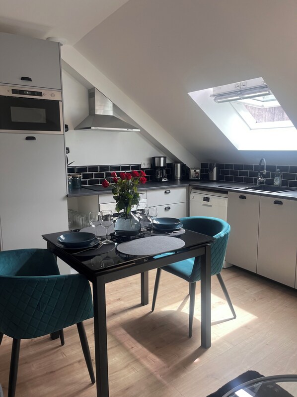 Una cocina moderna con tragaluz, armarios blancos y sillas color turquesa.