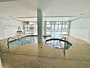 An indoor swimming pool with clear views of the outside, a lifeguard chair, and a pool ladder.