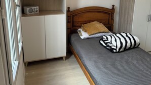 Una camera da letto con un letto, una testata in legno, un armadio bianco e una radio su uno scaffale.