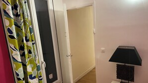 Una stanza con una porta, un tavolo con una lampada e una tenda decorata con un motivo a foglia.