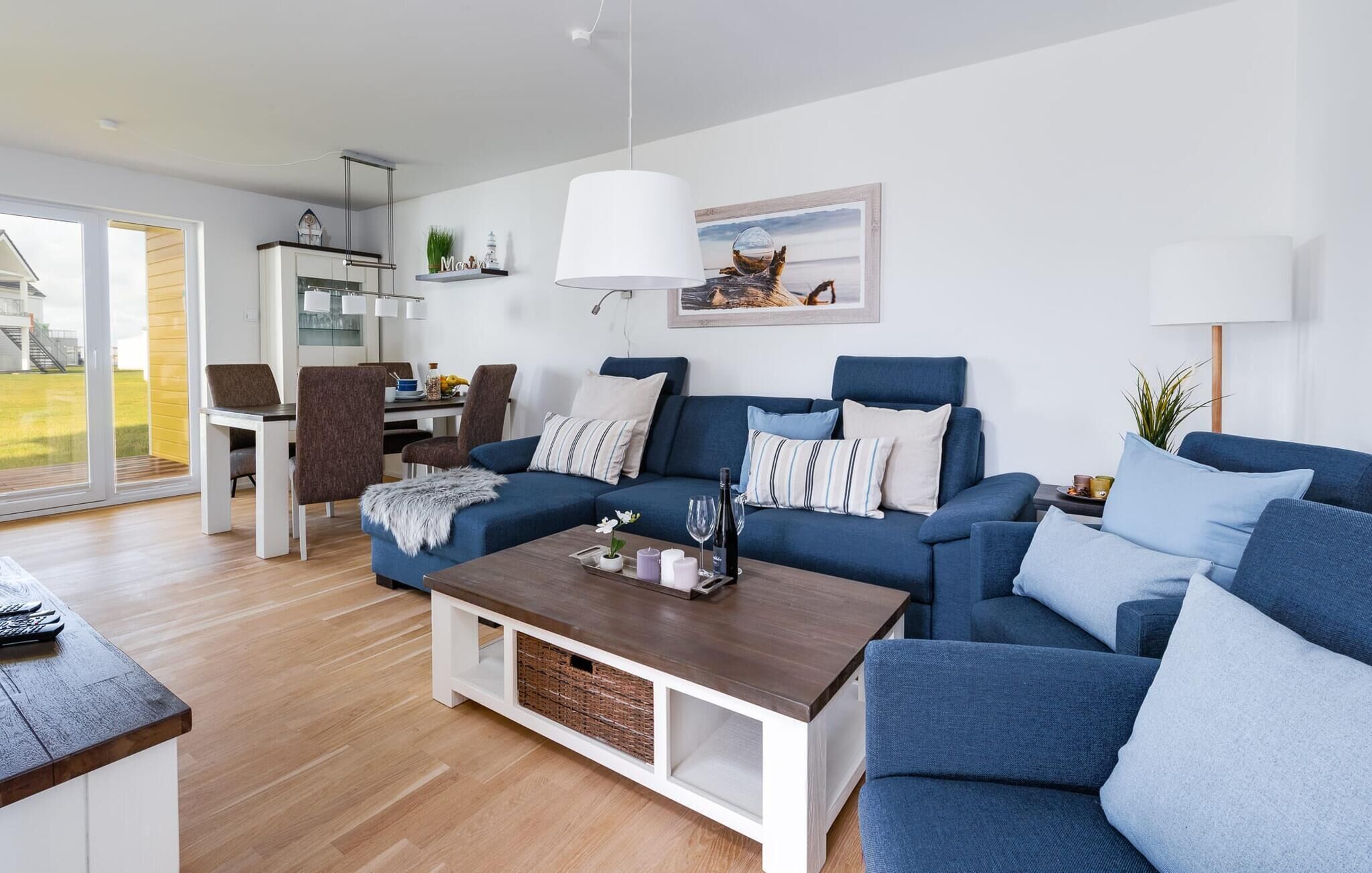 Ein modernes Wohnzimmer mit einem blauen Sofagarnitur, einem Holztisch und einem Essbereich mit Stühlen und einem Tisch.