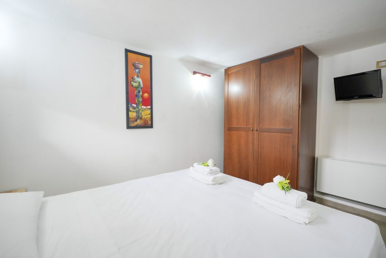 Une chambre d’hôtel avec un lit, une armoire, un tableau au mur et un téléviseur.