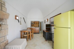 A compact kitchen with a dining table, chairs, a yellow refrigerator, and a small dining area.