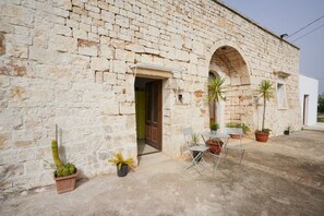 A stone building with a door, potted plants, and a table with chairs outside. - GuestHost - Bianca Luna Home - Apartment 2 (Città Metropolitana di Bari)