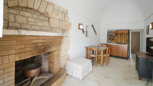 Ein Zimmer mit Kamin, Esstisch mit Stühlen, Küchenzeile und Fernseher.
