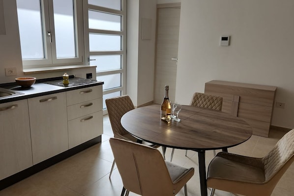 A modern kitchen with a round dining table, beige chairs, and a built-in bench.