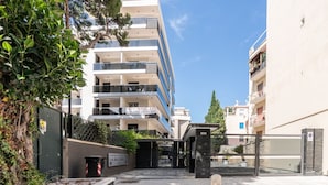 Un immeuble à plusieurs étages doté de balcons, d’une entrée sécurisée et d’une enseigne indiquant un numéro de téléphone à contacter.