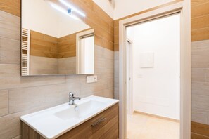 Un baño con lavamanos blanco, tocador de madera y espejo.