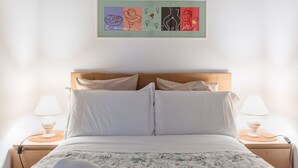 A neatly made bed with a floral bedspread, two bedside lamps, and a framed artwork above the bed. - GuestHost - Cozy and quiet apartment of 60 sqm, for 4 people, located on the 1st floor of a building (no elevator). The property is located near Piazza Dalmazia, from where the tram leaves to reach in a few minutes the Santa Maria Novella Station and the (Florence)