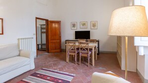 A living room with a sofa, a dining table with chairs, a TV, a lamp, and a patterned rug. - GuestHost - Cozy and quiet apartment of 60 sqm, for 4 people, located on the 1st floor of a building (no elevator). The property is located near Piazza Dalmazia, from where the tram leaves to reach in a few minutes the Santa Maria Novella Station and the (Florence)