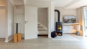 A modern living room with a wood-burning stove, a staircase, and a TV mounted on the wall.